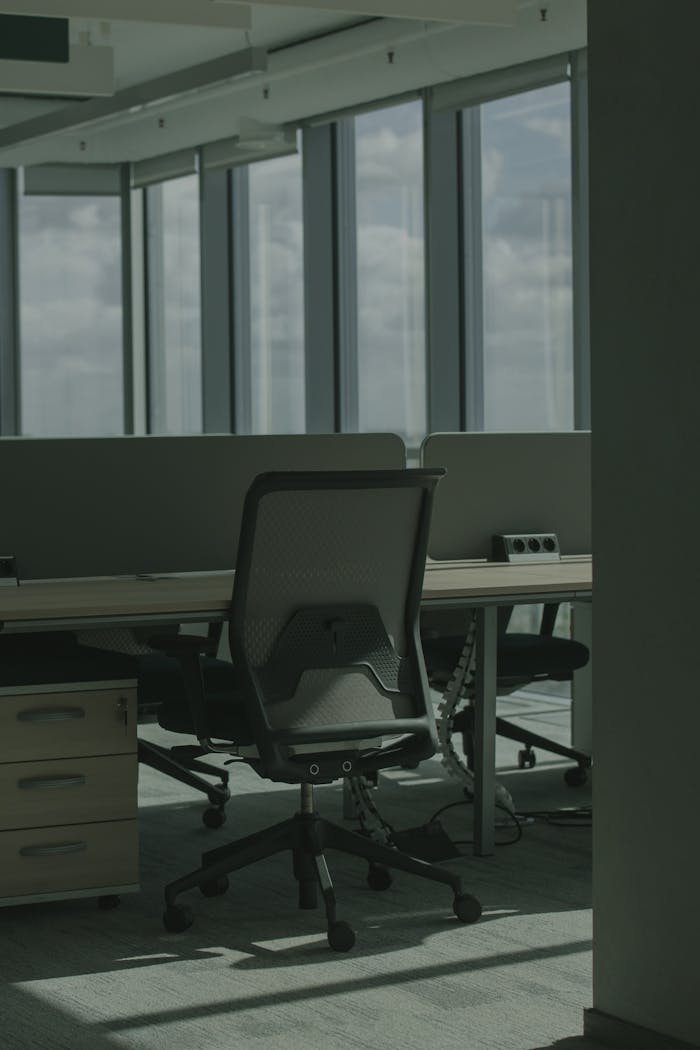 Empty office workspace with modern furniture and large windows overlooking the cityscape.