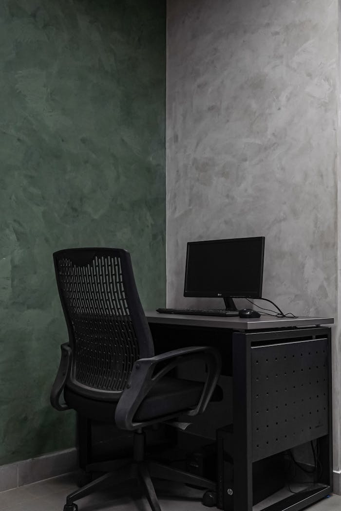 Simple modern office interior with a mesh chair and desk against textured walls.